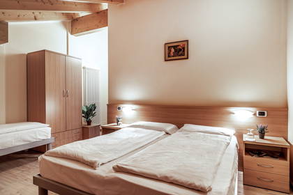 Pokój hotelowy z dwoma łóżkami, szafkami nocnymi i drewnianą szafą.