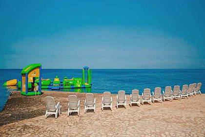 Plaża z leżakami i dmuchany park wodny na wodzie.