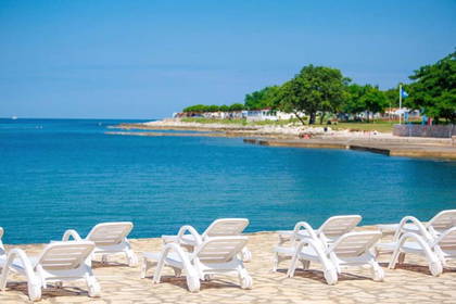 Białe leżaki na plaży z widokiem na morze.