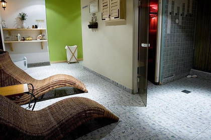 Wnętrze spa z wiklinowymi leżakami i sauną.