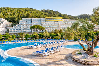 Basen hotelowy z leżakami. W tle budynek.