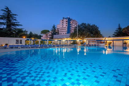 Hotelowy basen z błękitną wodą nocą.