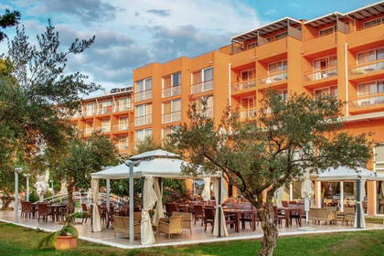 Pomarańczowy budynek hotelu z restauracją na świeżym powietrzu.
