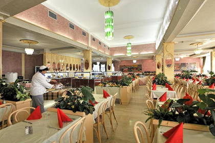 Restauracja z bufetem i kucharzem krojącym mięso.