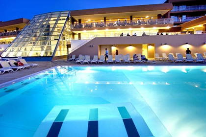 Basen hotelowy z leżakami i gośćmi.