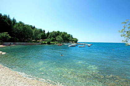 Plaża z krystalicznie czystą wodą, w tle bujna zieleń.