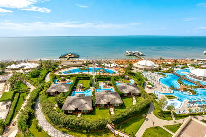 Widok z góry na luksusowy kurort z basenami, domkami i plażą.