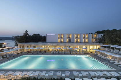 Hotel z basenem i leżakami o zmierzchu.