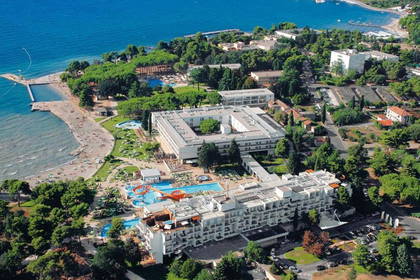 Zdjęcie lotnicze nadmorskiego kurortu z plażą, basenami i zielenią.