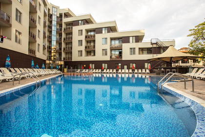 Basen hotelowy z leżakami i barem.