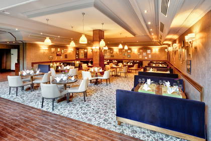 Wnętrze restauracji. Widoczne nakryte stoliki i oświetlenie.