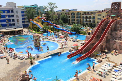Aquapark ze zjeżdżalniami i basenami, w których wypoczywają ludzie.