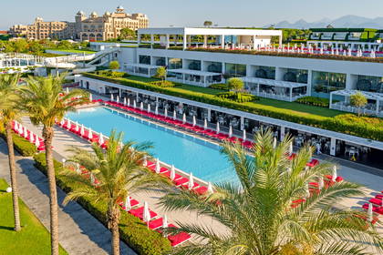 Hotelowy basen z leżakami otoczony palmami, widok z góry.