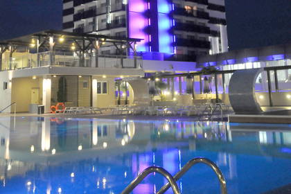 Hotel z basenem na dachu oświetlony nocą.