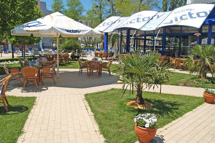 Restauracja na zewnątrz z parasolami i wiklinowymi krzesłami.