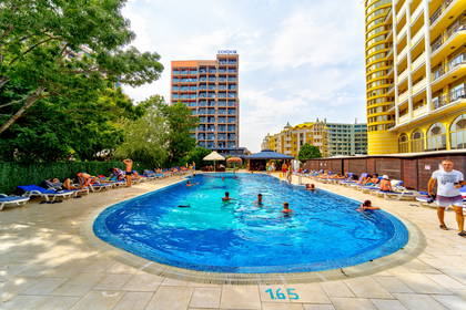 Basen hotelowy z leżakami i kąpiącymi się osobami.