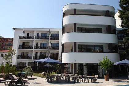 Biały hotel z balkonami i patio.