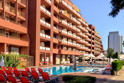 Hotel z basenem, leżakami i kasynem w tle.
