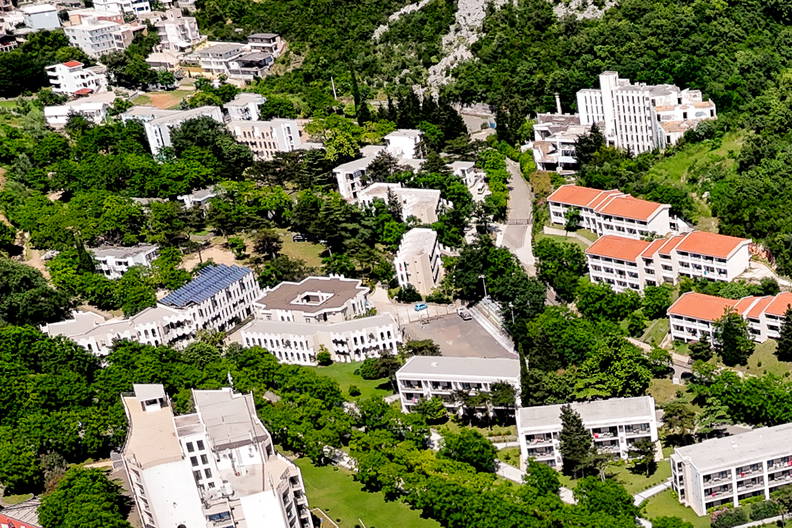 Kurort nad morzem widziany z góry. Na zdjęciu hotele, baseny i plaża z parasolami.