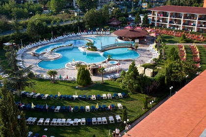 Kompleks basenowy z leżakami i budynkiem hotelowym, widok z góry.
