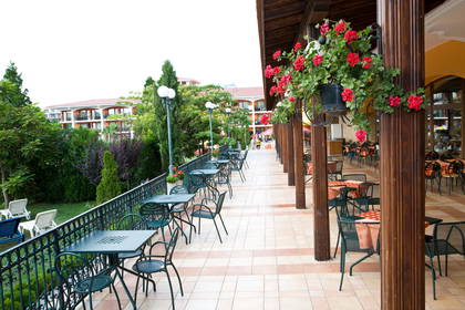 Patio restauracji z kwiatami, stołami i krzesłami.