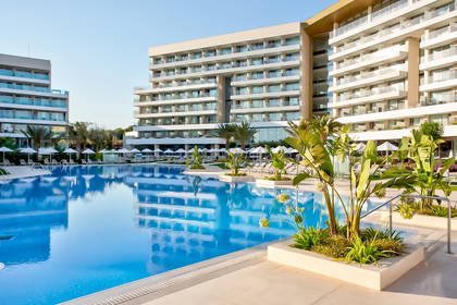 Kompleks hotelowy z basenem i leżakami do opalania.