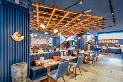 Restauracja z niebieskimi ścianami i drewnianym sufitem.