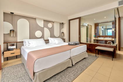 Pokój hotelowy z dwoma łóżkami i szafką nocną. Widok na łazienkę.
