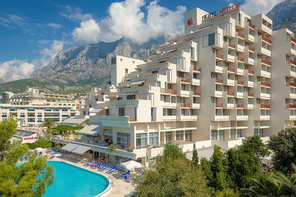 Hotel Meteor z basenem i górami w tle.