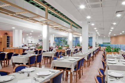 Przestronna restauracja z nakrytymi stołami.