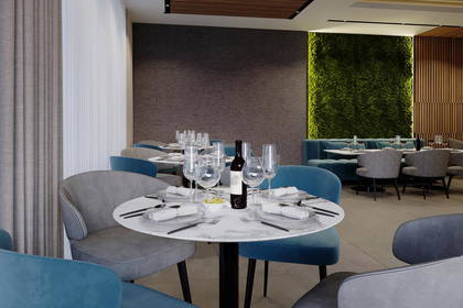 Restauracja z zieloną ścianą i nakrytymi stolikami.