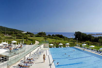 Basen hotelowy z leżakami i parasolami w słoneczny dzień.