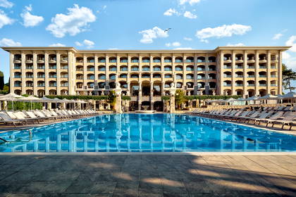 Hotel z basenem i leżakami w słoneczny dzień.