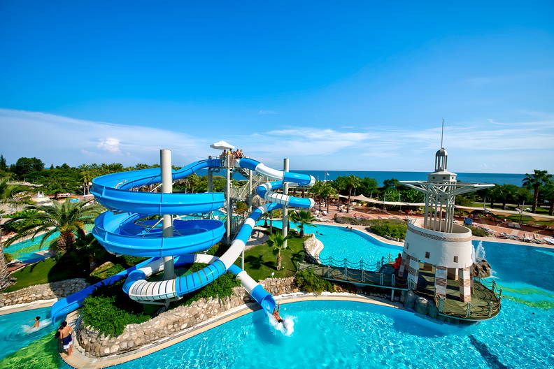 Kompleks basenów z niebieskimi zjeżdżalniami i wieżą.