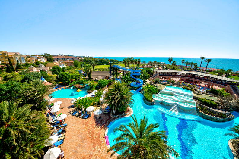 Kurort z basenami, zjeżdżalniami i palmami, widok z góry.