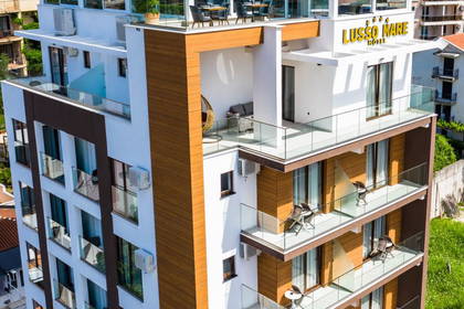 Wielopiętrowy hotel z balkonami i tarasem na dachu, widok z góry.