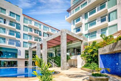 Kompleks hotelowy z basenem w tropikalnej scenerii.