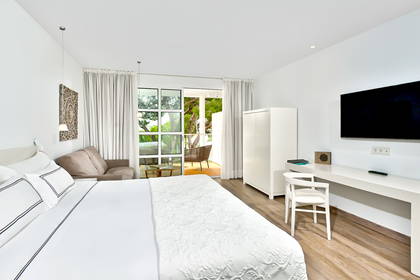 Jasny pokój hotelowy z łóżkiem, kanapą i balkonem.