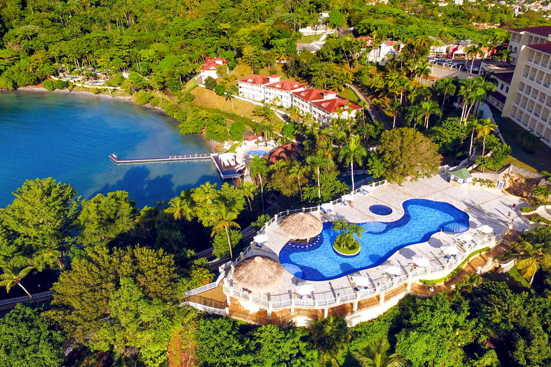 Widok z lotu ptaka na hotel z basenem, plażą i zielonym terenem.