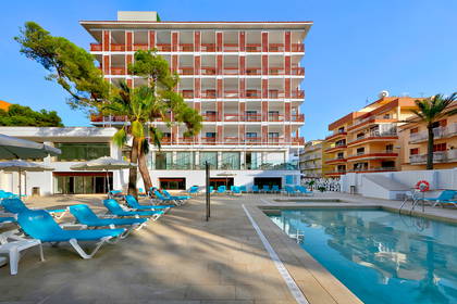 Hotel z basenem i leżakami w słoneczny dzień.