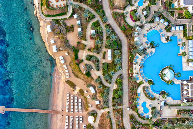 Kurort nad morzem z basenem, plażą i pomostem widziany z góry.