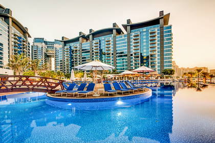 Kompleks hotelowy z basenem i leżakami do opalania.