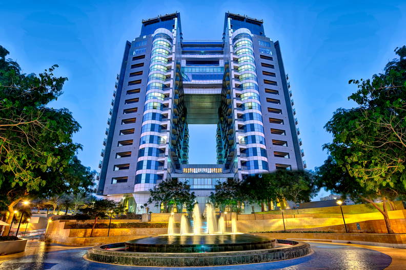 Dwie wieże połączone mostem i fontanna na pierwszym planie.