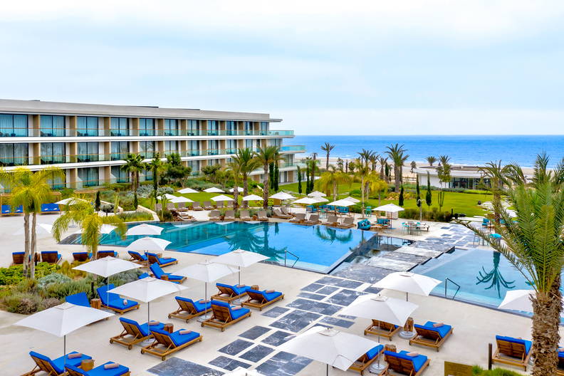 Luksusowy hotel z basenami, leżakami i palmami.