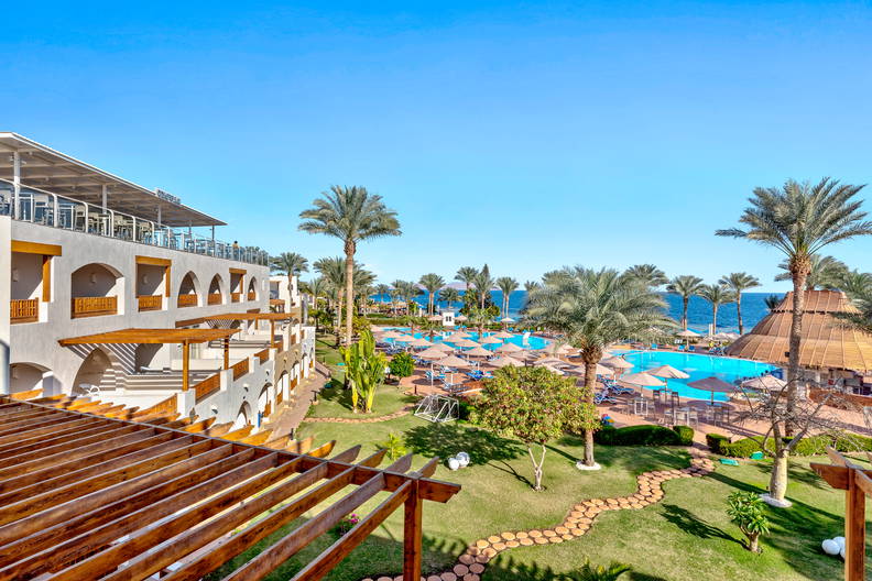 Kurort z basenem, palmami i widokiem na morze.