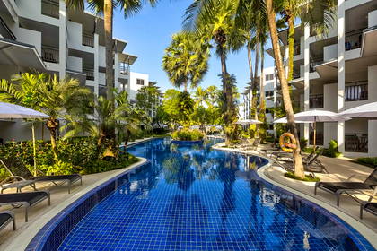 Kompleks hotelowy z basenem otoczonym palmami.