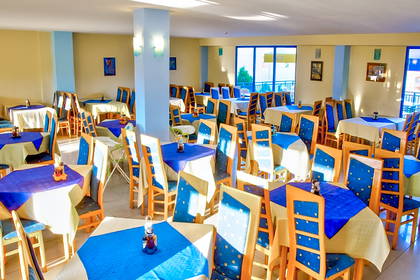 Jasna sala restauracyjna z nakrytymi stołami i krzesłami.