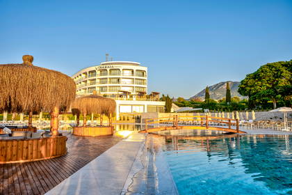 Hotel z basenem i drewnianymi altanami.