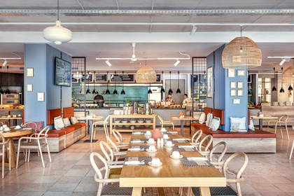 Jasne wnętrze restauracji z drewnianymi stołami i krzesłami.