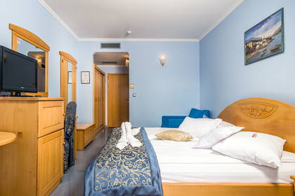 Pokój hotelowy z łóżkiem, telewizorem i jasnymi ścianami.